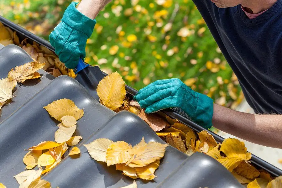 Hands clearing debris from a residential gutter